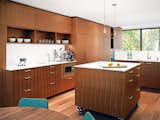 A movable island, set on stainless steel casters, sits in the center of the kitchen. The Panasonic microwave is built into the cabinetry and the August pendant lights illuminating the island are by Uberhaus.