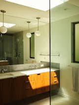 INAX tile is paired with walnut cabinets by Bellwether Millworks in the master bathroom, which also features Ladena sinks and Purist faucets from Kohler. The tab pulls are from Häfele, the Syncro floor tiles from Century, and the Niveous pendant from WAC Lighting.