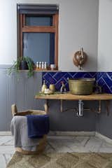 An old brass jam pan has been repurposed into the bathroom sink, while the tap is a reclaimed French copper kettle.