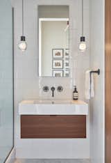 White ceramic tiles by Waterworks line the bathroom walls. The floors, also by Waterworks, are honed Carrara marble. The sink with an integrated top is by Duravit.