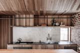 The kitchen backsplash comprises custom speckled white Anchor Ceramics tiles. Brodware taps are installed above a stainless-steel countertop and double sink.