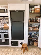 A small refrigerator and well-organized pantry outfit the kitchen.