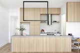 A graphic black lighting feature hangs above the kitchen bench, which conceals storage space behind oak doors.