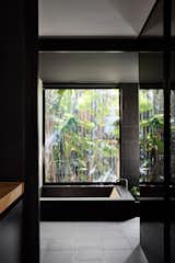 Enormous windows allow light to flood the interior, while carefully framed views of the garden blur the boundaries between interior and exterior. The deep concrete bathtub in the downstairs bathroom, for example, offers views of both internal and external gardens.