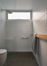 The bathroom is utilitarian, with simple matte white porcelain tiles and bluestone flooring. The tiling throughout, including the bluestone floor in the kitchen and deck, cost $6,000 ($3,500 USD).&nbsp;